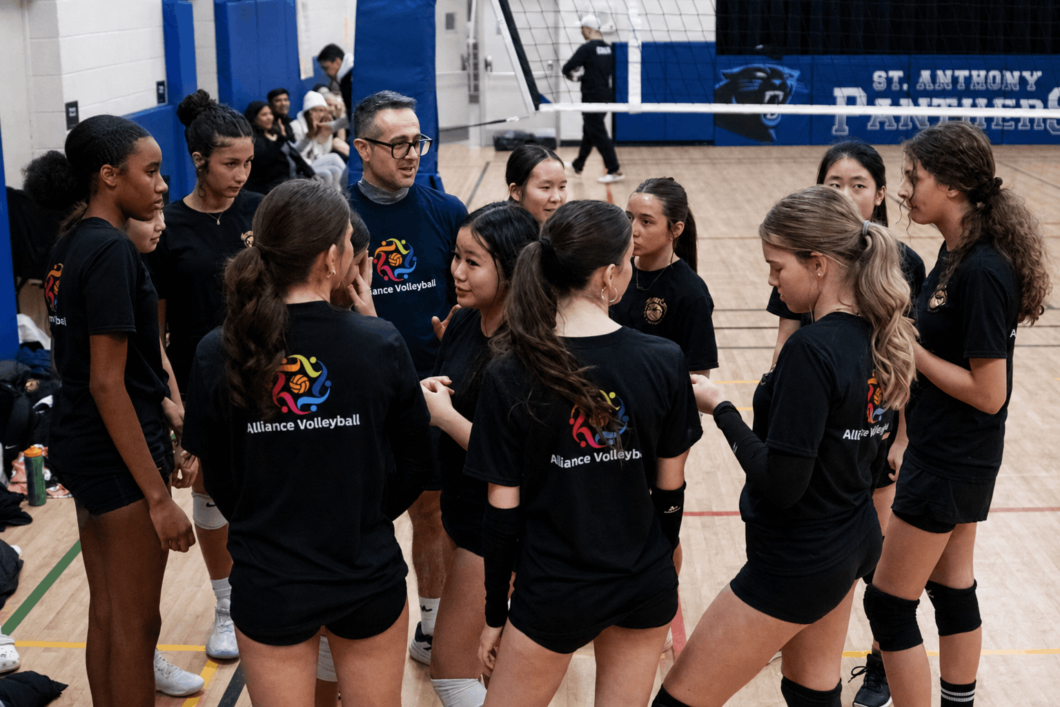 Alliance Volleyball coach guiding athletes during a team huddle
